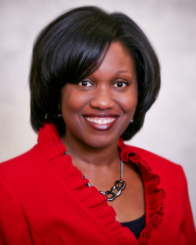 Headshot of Tabia Henry Akintobi wearing a red jacket