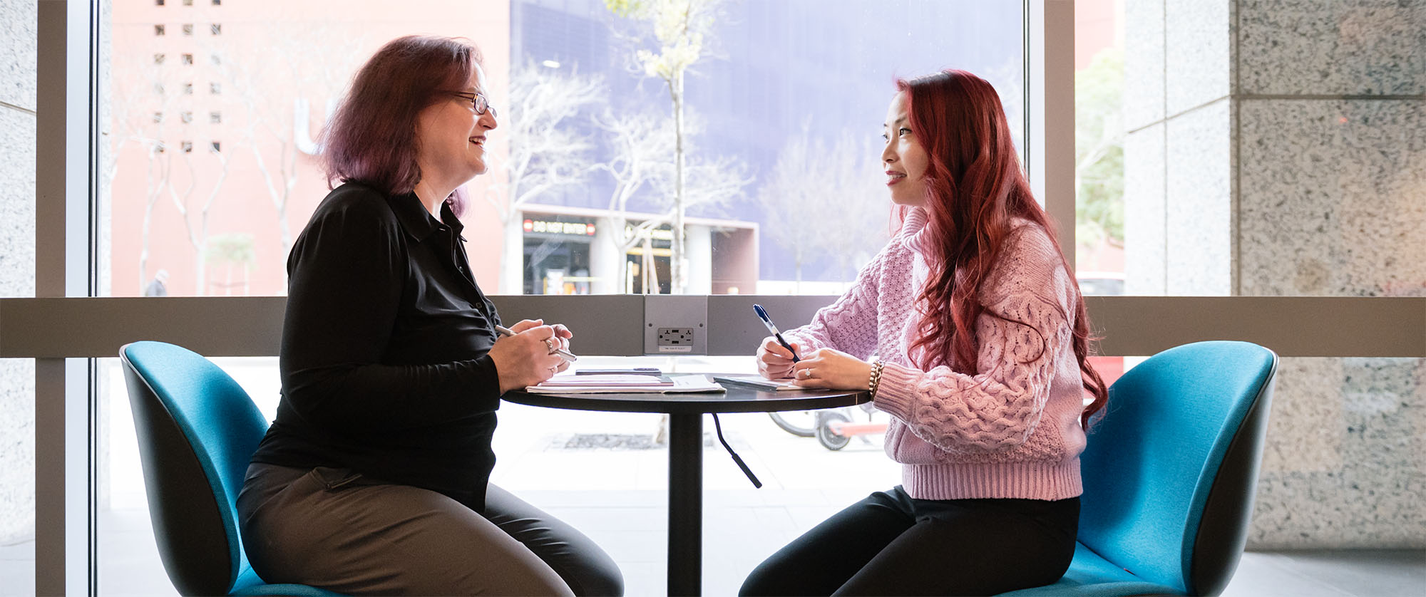 Bethany Taylor working with Loretta Ford at a small table in the Gladstone lobby