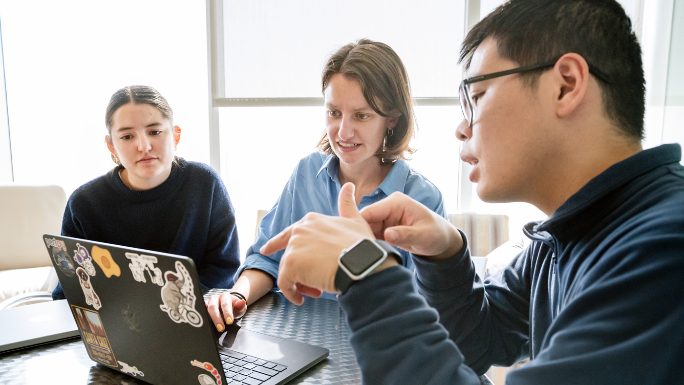 Members of the Marson Lab working together at a table with a laptop.