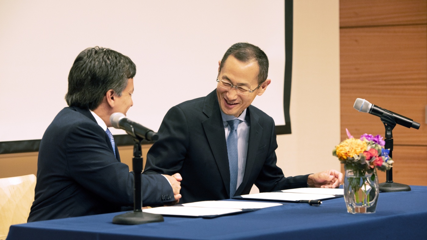 Deepak Srivastava and Shinya Yamanaka shake hands at a signing ceremony