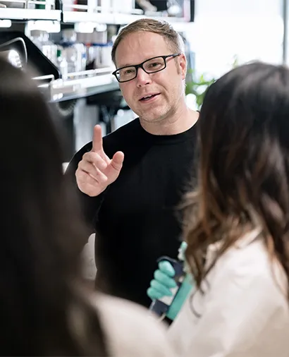 Magnus Hoffmann with his hand up talking to two other scientists
