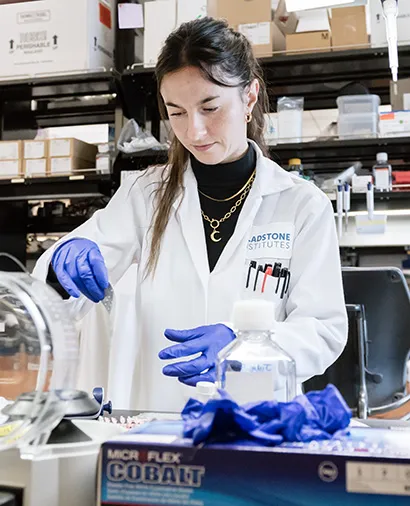 Scientist in a lab coat and gloves working on an experiment at a lab bench