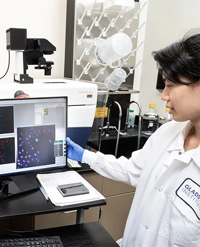 Scientist in a lab coat looking at a screen for a piece of lab equipment