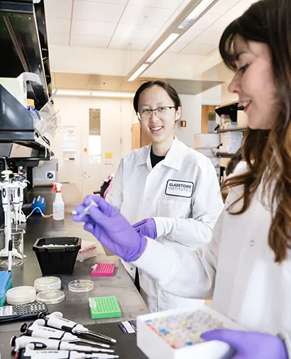 Two scientists in lab coats working at a lab bench together