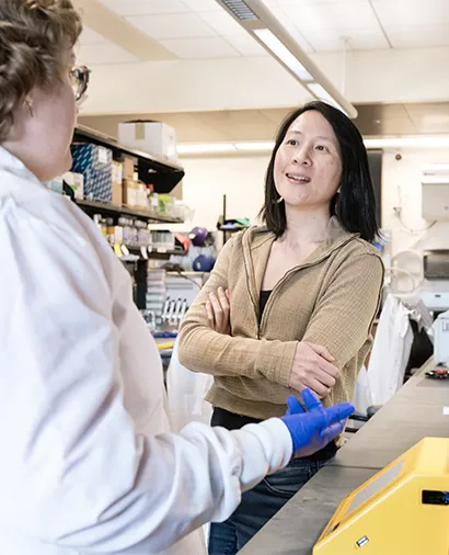 Nadia Roan standing at a lab bench, talking to another scientist in a lab coat