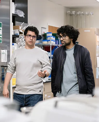 Vijay Ramani talking to another scientists while walking through the lab