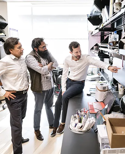 Deepak Srivastava, Michael Alexanian, and another scientist discussing something on a computer screen at a lab bench