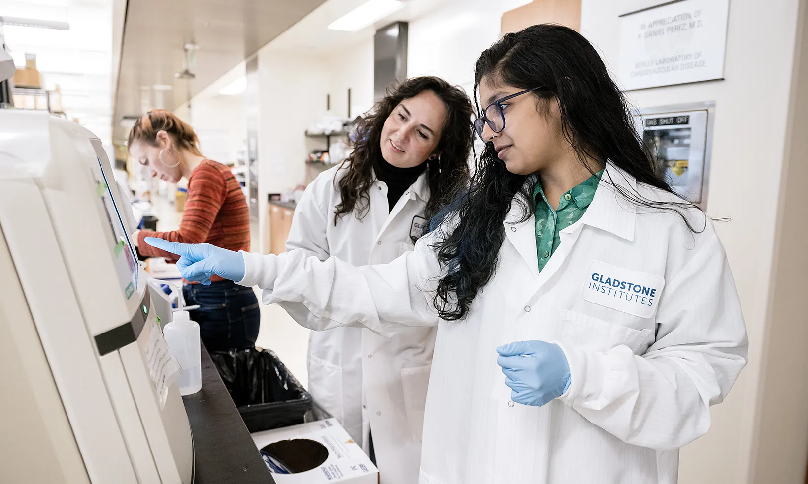 Two scientists in lab coats working with a piece of a equipment in the lab