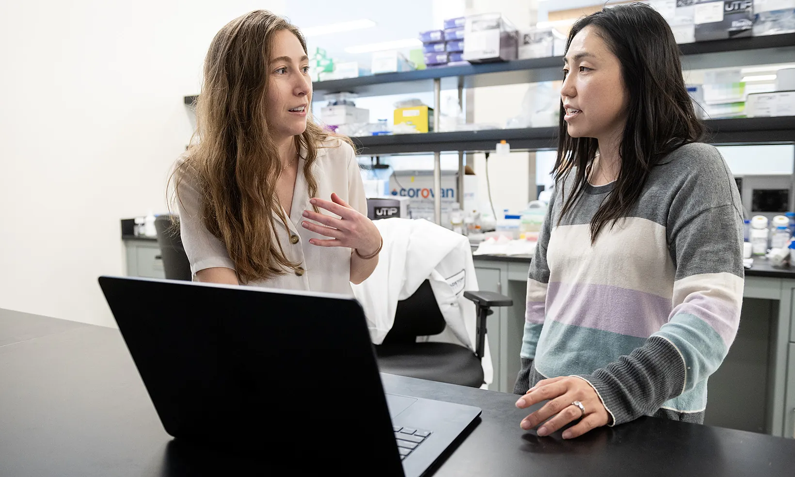 Two scientists working together at a laptop in a lab
