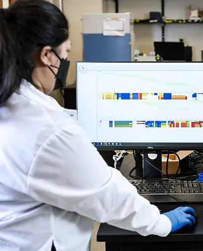 Scientist facing away from the camera looking at a computer screen with data