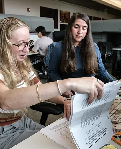 Christina Theodoris working with a scientist while sitting down at a computer going through papers