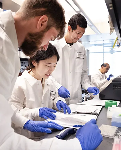Three scientists going over their lab notes at a lab bench