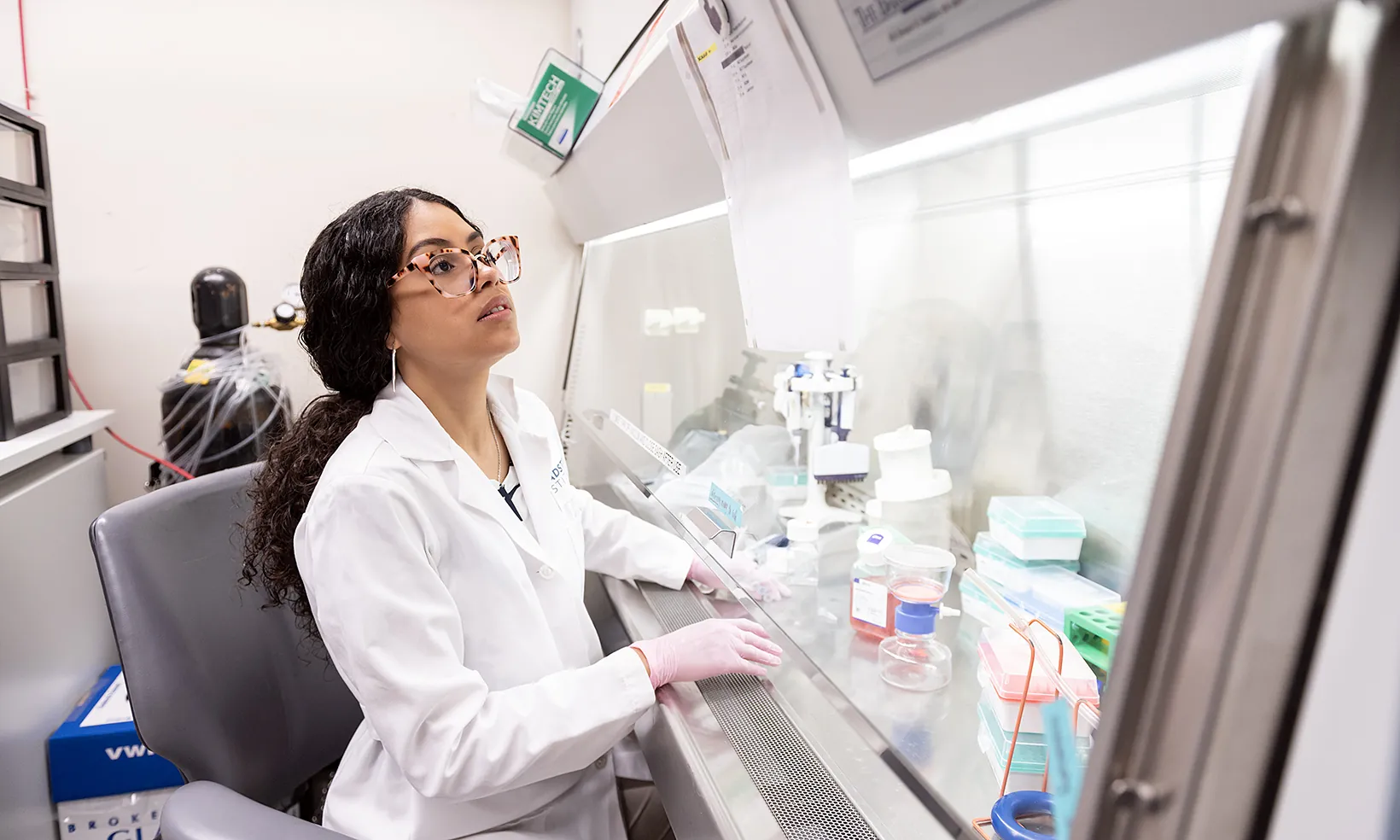 A graduate student researcher working on an experiment at a lab bench.