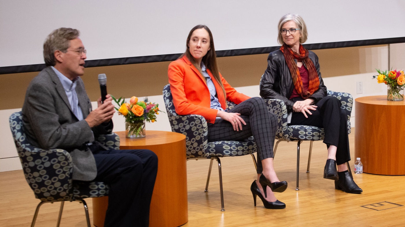 Three scientists sitting on a stage talking to an audience