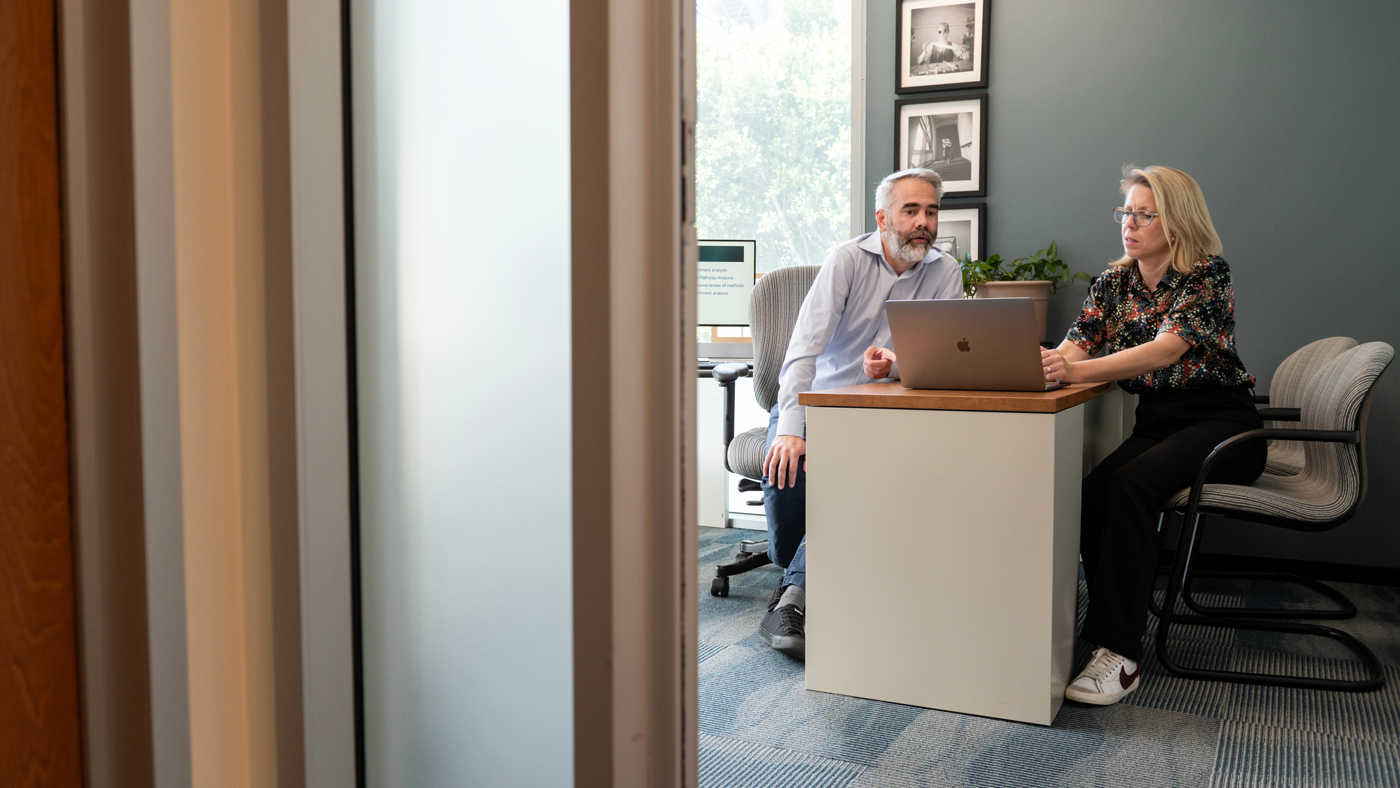 Alex Pico and Kristina Hanspers sitting at a desk discussing something over a laptop
