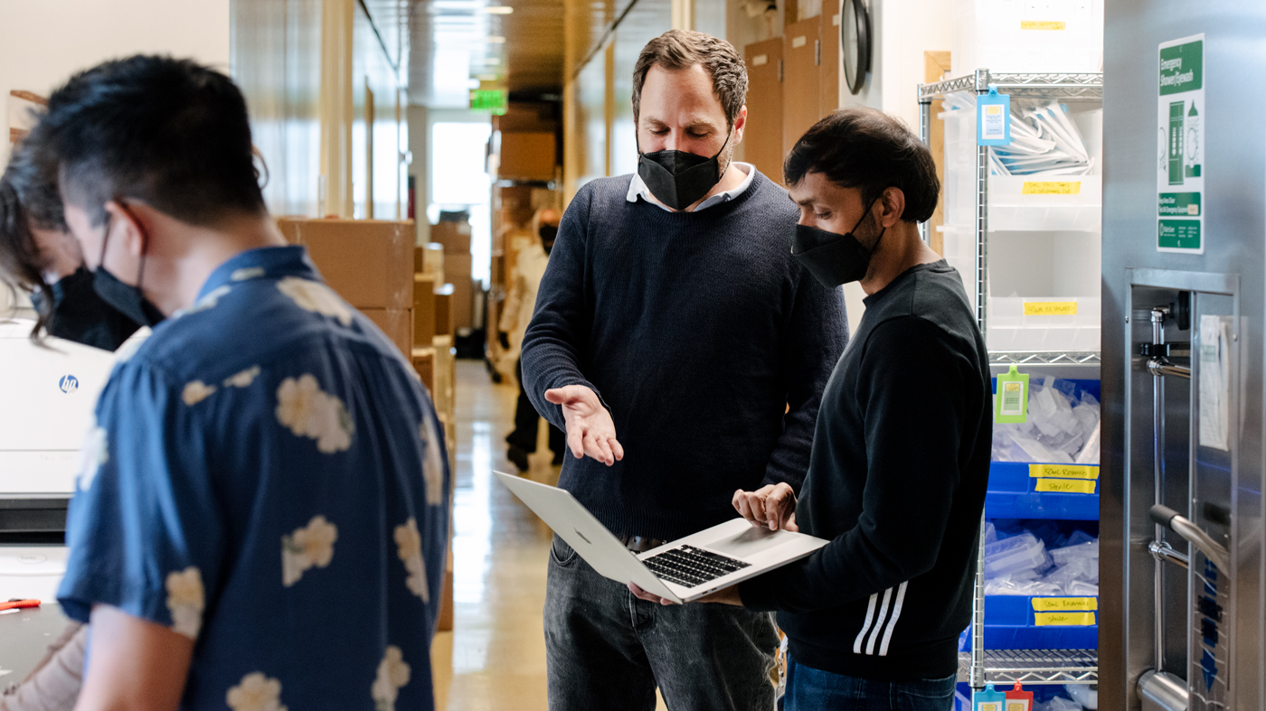 Alex Marson in the lab at Gladstone Institutes, speaking with Ujjwal Rathore