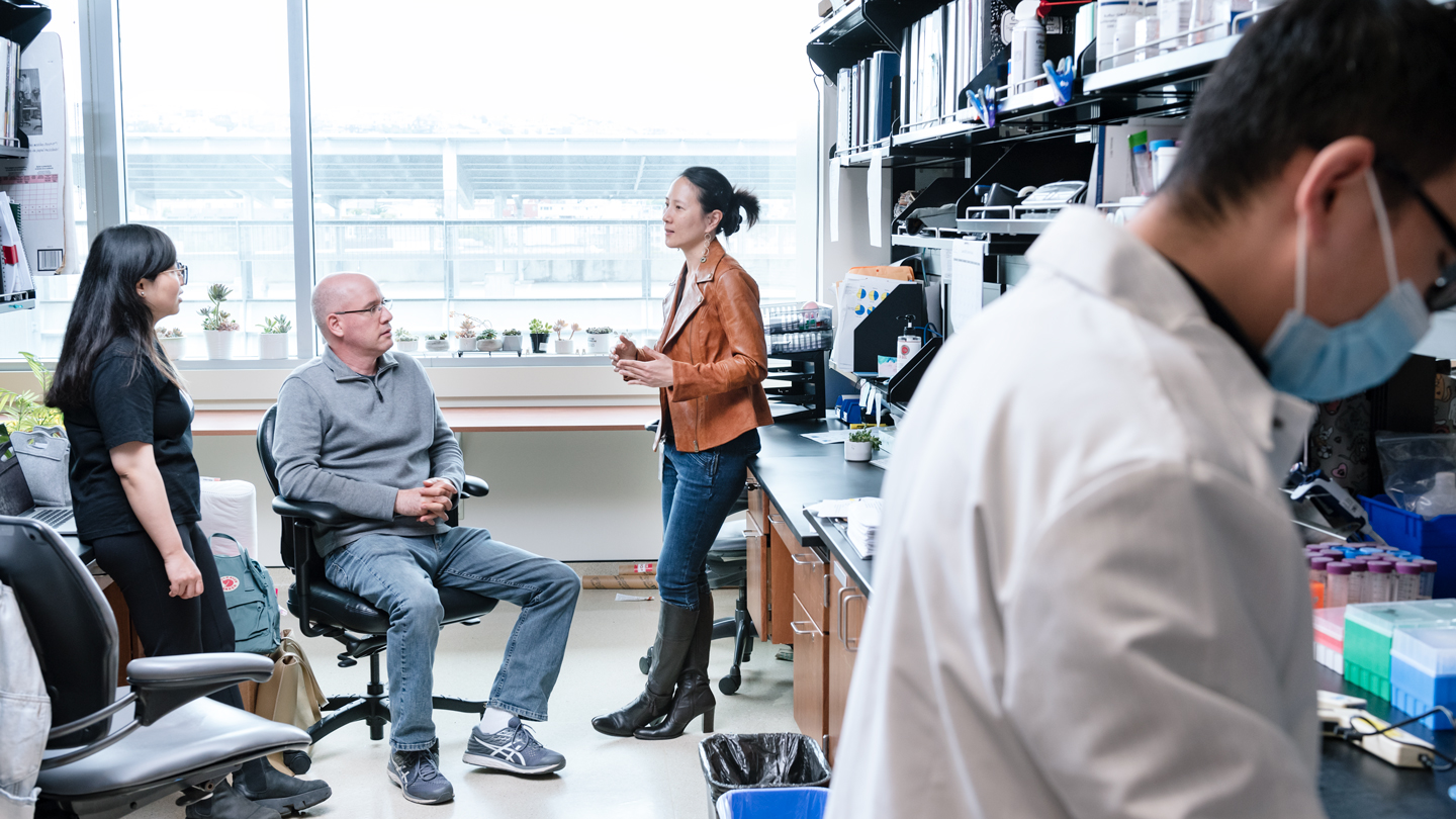 Nadia Roan talking to two researchers in the lab